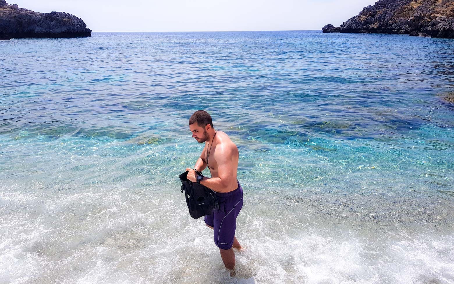 man preparing to snorkel on a greek beach