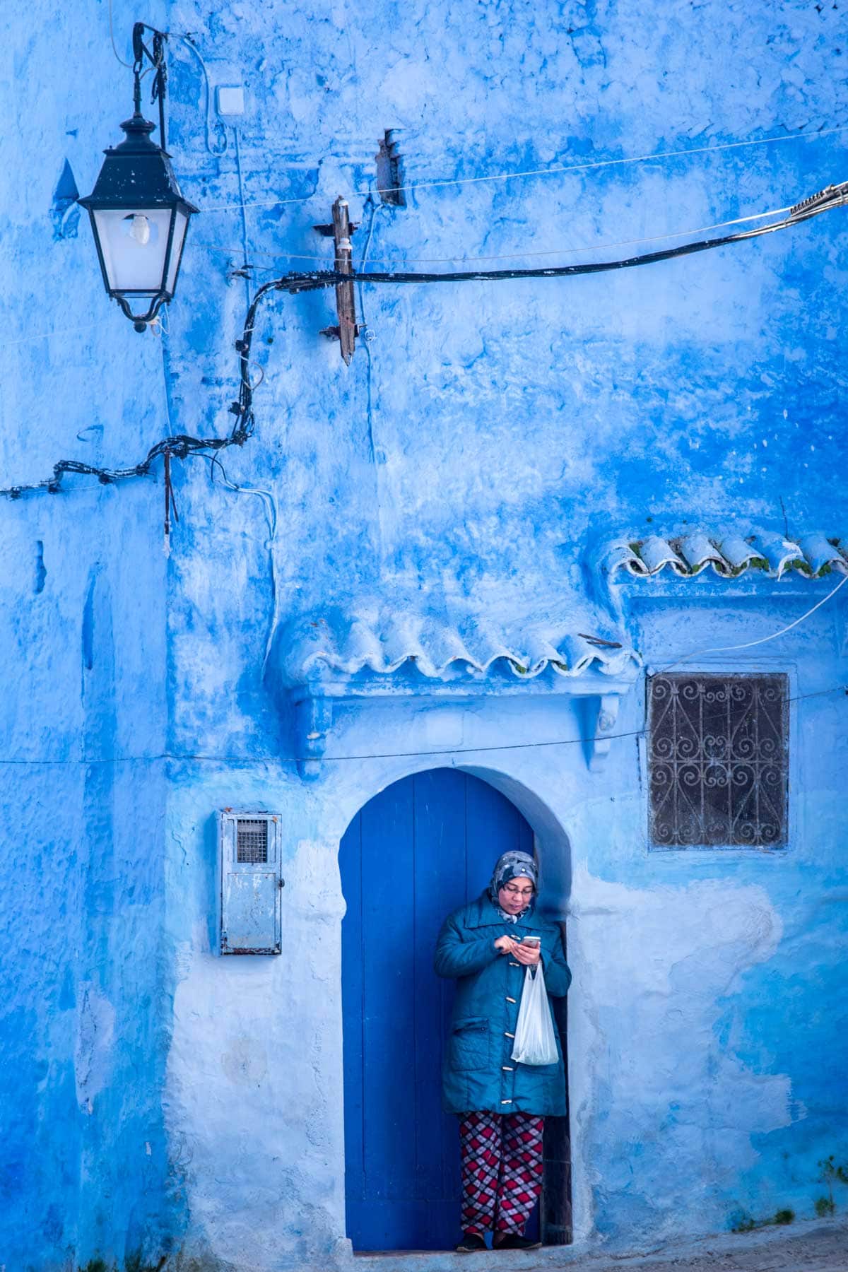 what is morocco famous for- girl looking at her phone in the blue citiy