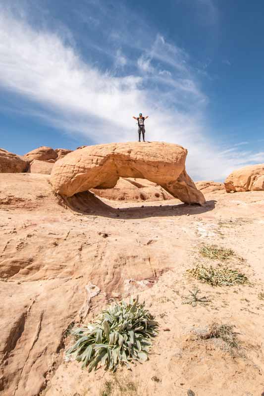 man staying on a rock arch in wadi rum