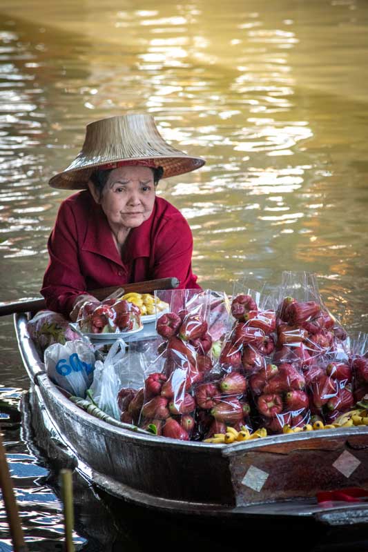old woman selling fruits on a boat at damnoen-saduak-floating-market