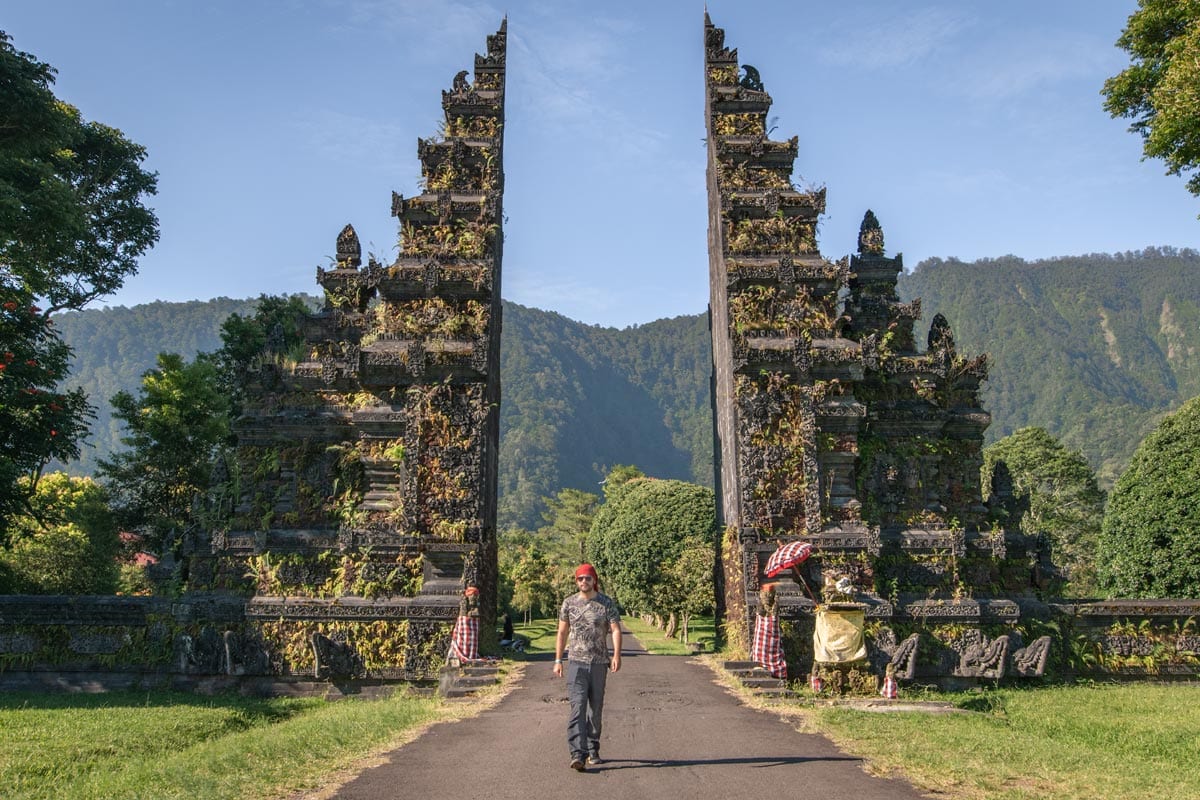 man-walking-in-front-of-a-traditional-balinese-stone-gate