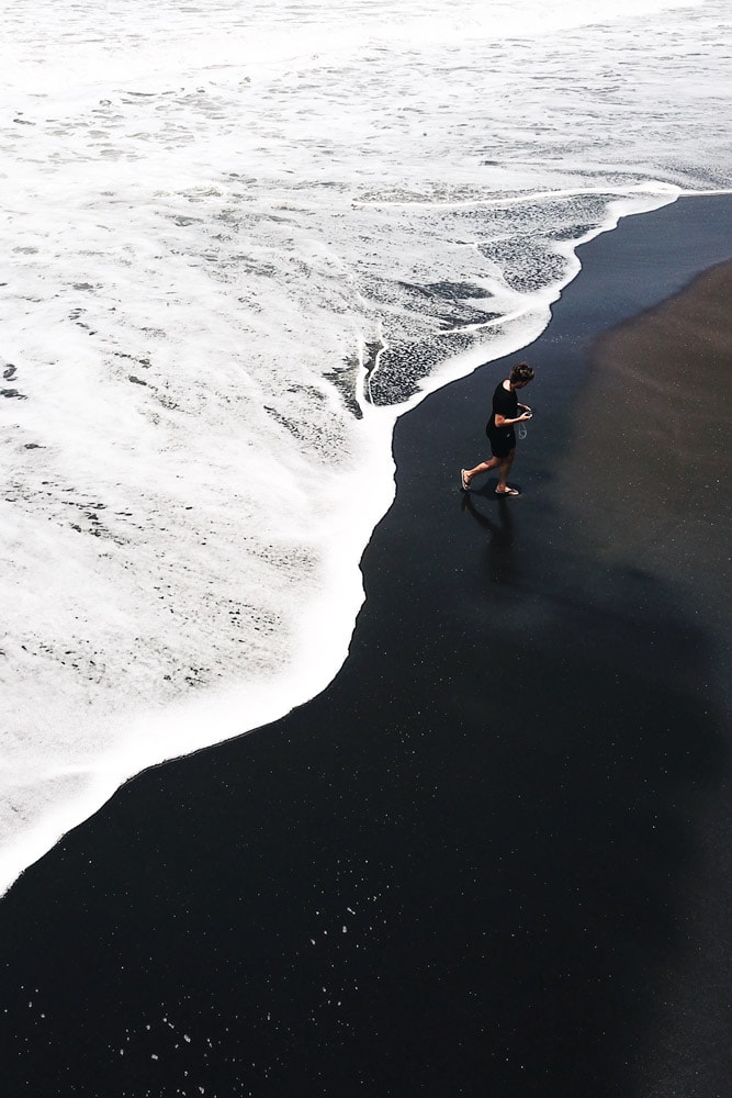 man-walking-on-a-black-sand-beach