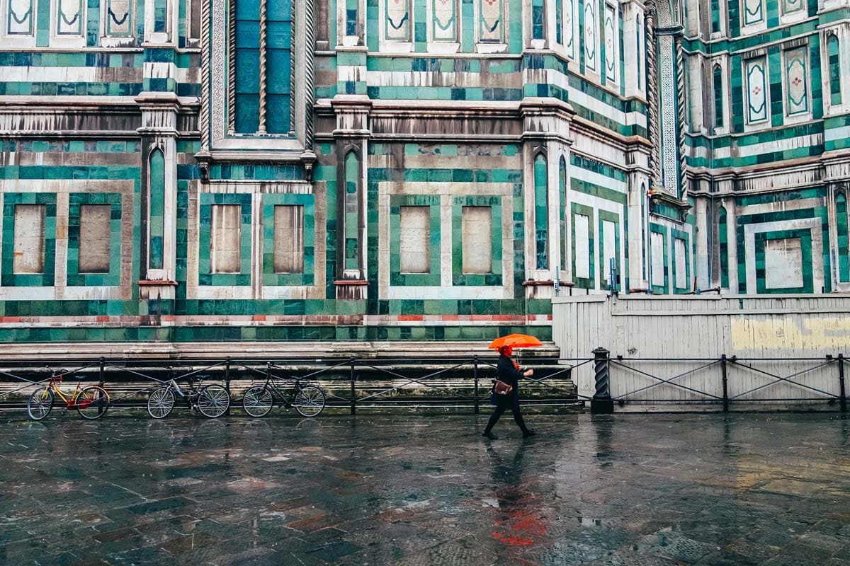 man-with-orange-umbrella-walking-in-front-of-colorful-building