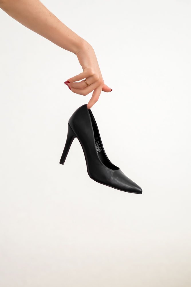 a-hand-holding-a-black-high-heel-shoe