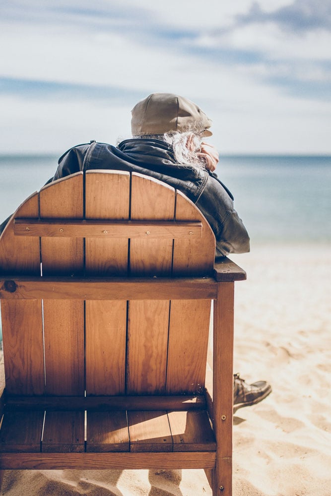 old-man-sitting-on-a-chair-on-the-beach-watching-the-ocean