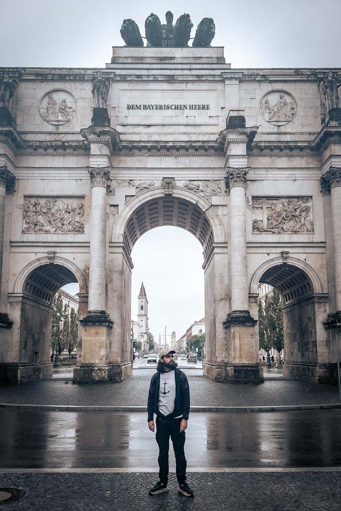 man-in-fron-of-a-triumphal-arch-in-munich