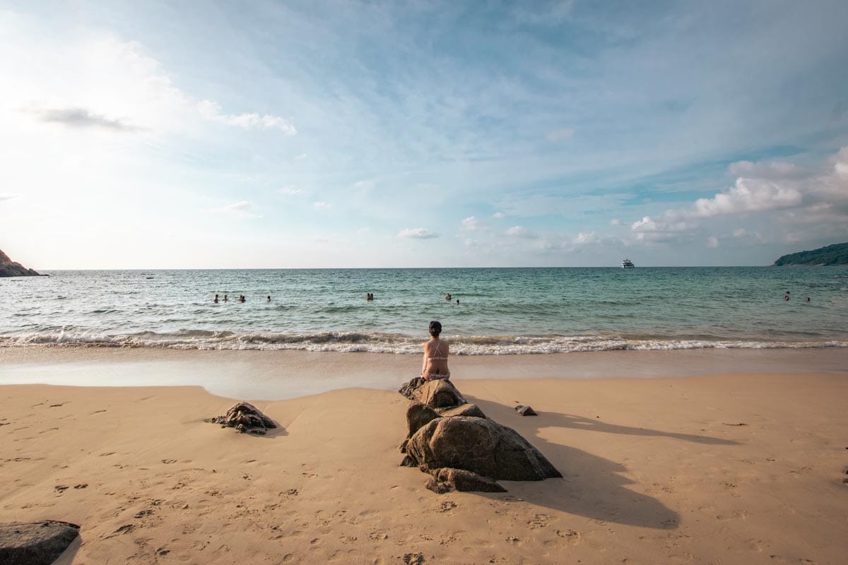 best-beaches-in-phuket-girl-sitting-on-a-rock