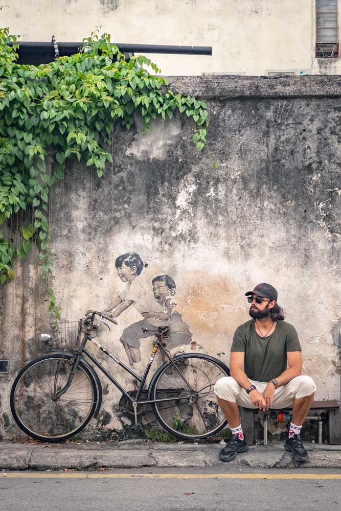 what-to-see-in-penang-man-sitting-next-to-a-mural